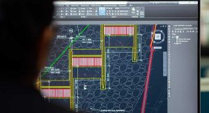 autocad: a man sitting in front of the screen with AutoCAD software running