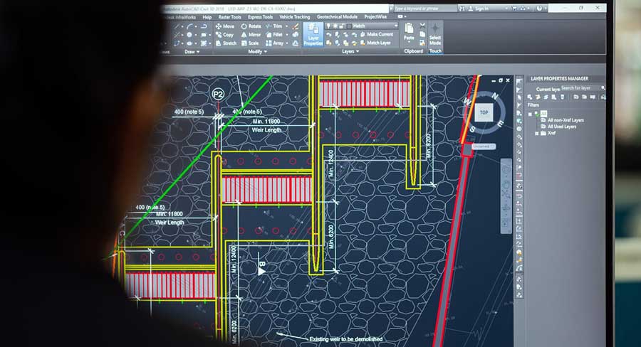 autocad: a man sitting in front of the screen with AutoCAD software running