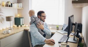 mechanical engineer working from home with baby on his shoulder